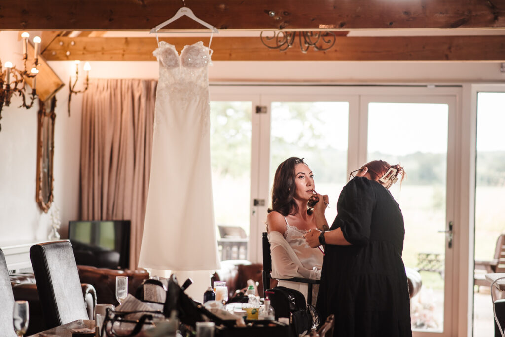 Bride during bridal prep with the dress in the background