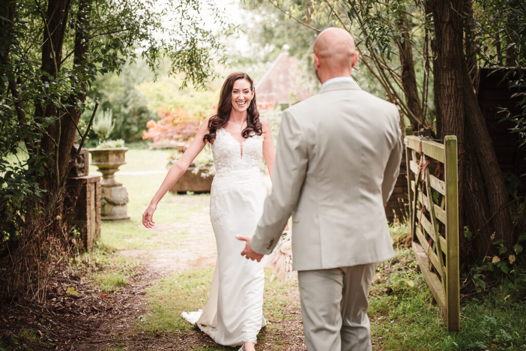 Bride walking towards the groom during their woodland photo session