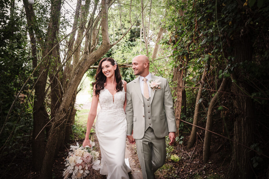 Groom looking at bride happy during their woodland walk