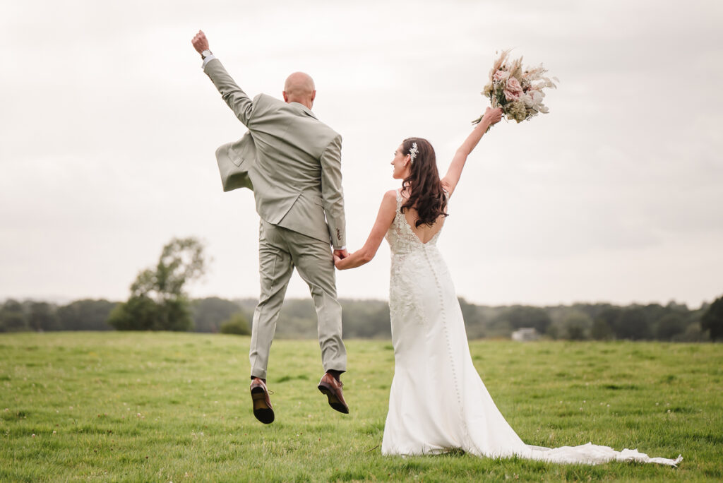 Groom jumping with happiness while bride has her flowers in the air