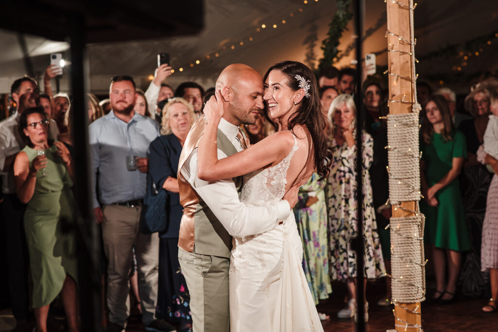 Bride smiling while groom holds her close during the first dance